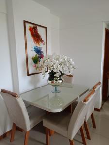 una mesa de comedor con sillas y un jarrón de flores en Solaris Residencial Clube, en Ilhéus