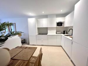 eine Küche mit weißen Schränken und einem Tisch und Stühlen in der Unterkunft Beach LUXURY - ALTEA Puerto de Campomanes in Altea