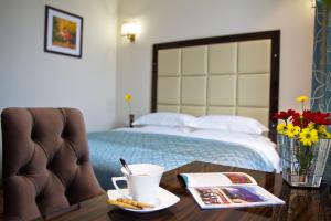 Un dormitorio con una cama y una mesa con una taza de café. en Garden Hotel, en Bishkek