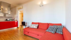 a red couch in a living room with a kitchen at Sardinianworld - Otton House in Oristano