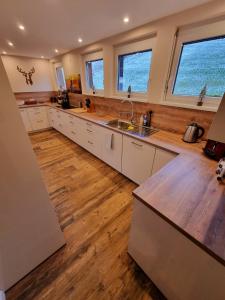 Il comprend une grande cuisine avec des placards blancs et du parquet. dans l'établissement "Deluxe" Ferienwohnung Schwarzwald, 8 Personen, 140 qm, Haus Sonnenschein, 2 Balkone, à Todtnau