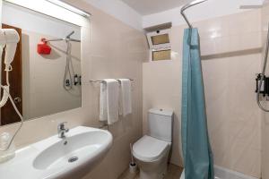 a bathroom with a sink and a toilet and a mirror at Guest House Oliveira in Boliqueime