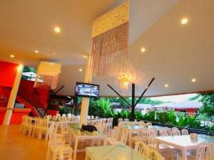 un salón de banquetes con mesas blancas y sillas blancas en Aurora Resort Kanchanaburi, en Kanchanaburi