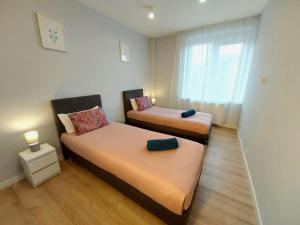 zwei Betten in einem kleinen Zimmer mit Fenster in der Unterkunft Avanti Apartments in Białystok