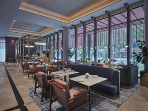 新加坡Pullman Singapore Hill Street的有桌椅和大窗户的餐厅