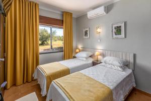 a hotel room with two beds and a window at Guest House Oliveira in Boliqueime