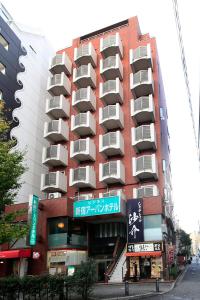 a tall red building with signs in front of it at Shinjuku Urban Hotel in Tokyo