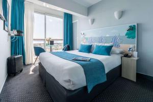 a hotel room with a large bed with blue accents at Best Western Hôtel Royan Océan in Royan
