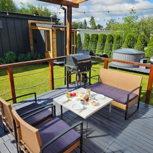 eine Terrasse mit einem Tisch, Stühlen und einem Grill in der Unterkunft Star One Wypoczynek Domek Jezioro Białe in Okuninka