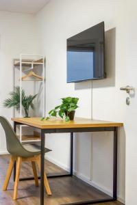 a desk with a television on a wall with a chair at Salí Homes Weinblick Beethoven - ruhige Feldlage in Obersulm +2 photos