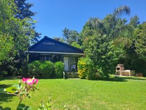 ein kleines Haus mit einem Garten mit einer rosa Blume in der Unterkunft La Caleta in Tigre