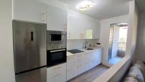 a kitchen with white cabinets and a stainless steel refrigerator at Ekain's Home -Sirimiri Apartments- in Zumaia