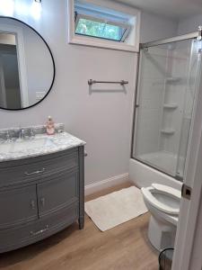 Un baño con lavabo, inodoro y espejo. en 4 Bedroom Cape Getaway, 5 Min Drive to Beach, Pool Table, Grill, Backyard, en Falmouth