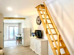 un soggiorno con scala, TV e frigorifero di "L'Echapée Belle" Maison de village climatisée de 45m2 à proximité de Carcassonne,1 chbre à l'étage vue panoramique sur les pyrénées, cuisine équipée,1Salon,1 sdb, Wifi, Parking gratuit, Netflix,Canal sat, Fauteuil massant a Montréal