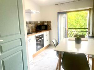 una cucina con tavolo e tavolo e una finestra di "L'Echapée Belle" Maison de village climatisée de 45m2 à proximité de Carcassonne,1 chbre à l'étage vue panoramique sur les pyrénées, cuisine équipée,1Salon,1 sdb, Wifi, Parking gratuit, Netflix,Canal sat, Fauteuil massant a Montréal
