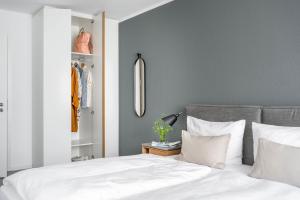 フリードリヒスハーフェンにあるBodenseeApartment Kammerの白いシーツと鏡が付いたベッドのある寝室