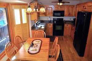 a kitchen with a wooden table with chairs and a black refrigerator at Little Heaven in Young Harris