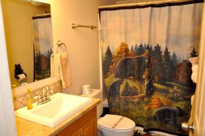 a bathroom with a shower curtain with a bear in a forest at Little Heaven in Young Harris +40 photos