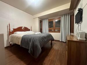 une chambre avec un lit et une télévision dans l'établissement Apartamento Coração de Gramado, à Gramado