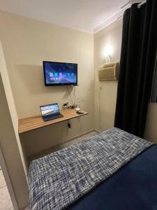 a bedroom with a bed and a desk with a television at Apt Central Caraguá in Caraguatatuba