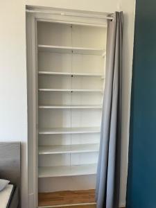 un armario con estanterías blancas y una cortina en Studio 6 Proche Centre Ville avec Wifi Parking Troyes, en Troyes 4 fotos más