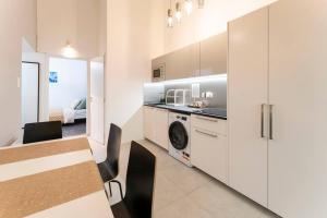 a kitchen with white cabinets and a table with chairs at Bolero2 apartman in Budapest
