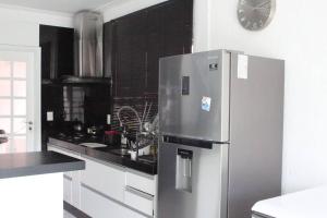 a kitchen with a refrigerator and a clock on the wall at 4suites arcond wifi600meg cond fech prox praia in Bertioga