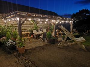 a patio with a table and chairs under a pergola with lights at Abbey Green Farm in Wem