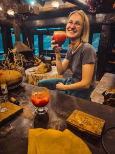 Una donna che regge un drink davanti a un bancone di Wolf Totem Steam Punk Guesthouse a Písac