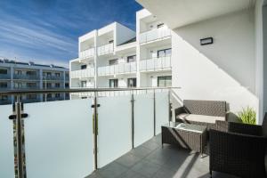 a balcony with chairs and a white building at SUNSET RESORT APARTAMENT KaPi in Grzybowo