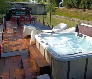 wanna z hydromasażem na tarasie ze stołem i krzesłami w obiekcie Péniche Mirage-chambre d'hôtes w Carcassonne