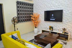 a living room with a yellow couch and a tv at SEGXYCOLD VALLEY OASIS Elegant 2-Bedroom Apartment in Agege