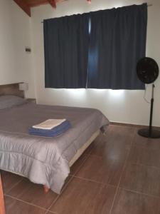 Un dormitorio con una cama y una ventana con ventilador. en Los Colibríes, en Lago Puelo
