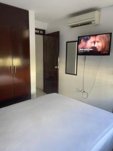ein Schlafzimmer mit einem Bett und einem Fernseher an der Wand in der Unterkunft Apartamento moderno cerca al aeropuerto in Neiva