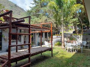 eine Terrasse mit einer Holzbank und einem Tisch und Stühlen in der Unterkunft Pousada Tarkna in Teresópolis
