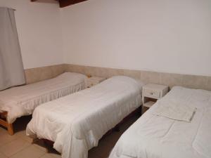 three beds in a room with white sheets on them at Mardifiore 1 ORO in General Madariaga