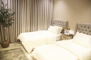 リヤドにあるرايا 03 raya القماريの白いシーツが敷かれたホテルの部屋にベッドが2つある