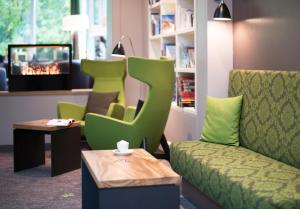 una sala de espera con sillas verdes y una mesa en Hotel Munte am Stadtwald, en Bremen