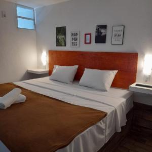 a bedroom with a large bed with a wooden headboard at Pousada Tarkna in Teresópolis