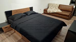 a bedroom with a black bed and a couch at Rebeka Luxury Apartment in Tryavna