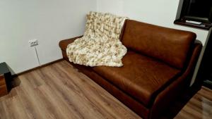 a brown leather couch with a blanket on it at Rebeka Luxury Apartment in Tryavna