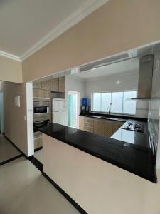 a large kitchen with a black counter top at Casa grande pé na areia Peruibe in Peruíbe