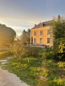 une grande maison jaune avec un chemin de gravier devant elle dans l'établissement La Galotière, à Ingrandes-de-Touraine