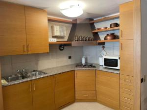 a kitchen with wooden cabinets and a sink and a microwave at Da NOEMI E MARCO in Cavalese