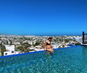 a woman in a bikini sitting on the edge of a swimming pool at Excepcional One bedroom Suite in Cabo San Lucas