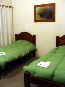 two beds in a room with green sheets at Finca Puesta del sol in San Agustín de Valle Fértil