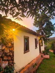 a small house with a stone wall and a window at Diamantina, Curralinho Extração in Diamantina