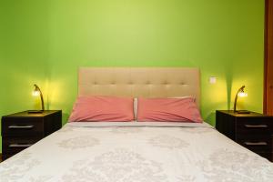 a bedroom with green walls and a bed with a pink pillow at Green Doors - AC and free parking in Machico