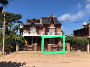a house with a green structure in front of it at Casa Dúplex Nueva Atlantis - Complejo San Norberto in Mar de Ajó