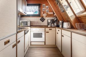 cocina con electrodomésticos blancos y techo de madera en 50100 Haus Marie, en Carolinensiel 8 fotos más